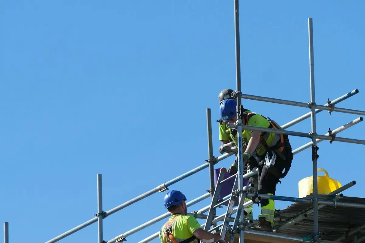 Workers in hard hats and harnesses on scaffolding